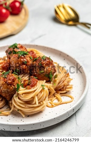 Meatballs served over italian spaghetti pasta with tomato sauce on a light background. Italian food. vertical image. top view. place for text,