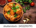 Meatballs with tomato sauce and parsley in bowl on rustic wooden table background. Top view