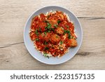 Meatballs in tomato sauce with pasta spirals lying on a plate on the table.