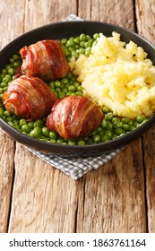 meatballs wrapped in bacon faggot with green peas and mashed potatoes close-up in a plate on the table. vertical