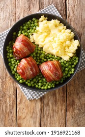 meatballs wrapped in bacon faggot with green peas and mashed potatoes close-up in a plate on the table.