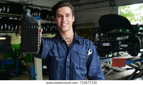 In a mechanic a\
mechanic after checking the oil and engine at the car smiles\
showing the oil tank used. Concept of: security, safety, insurance\
and professionalism,\
revisions.