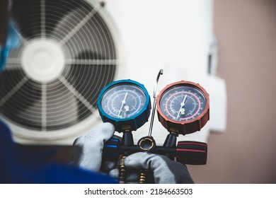 Mechanic Air Conditioner Technician Using Manifold Gauge Checking Refrigerant For Filling Home Air Conditioning And Air Duct Cleaning And Maintenance Outdoor Compressor Unit.