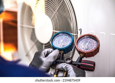 Mechanic air conditioner technician using manifold gauge checking refrigerant for filling home air conditioning and air duct cleaning and maintenance outdoor compressor unit.
