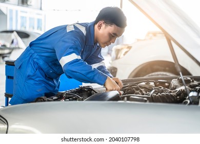 Mechanic Asian man fixing repairing car engine automobile vehicle parts examining screwing using tools wrench equipment working hard in workshop garage support and service in overall work uniform - Powered by Shutterstock