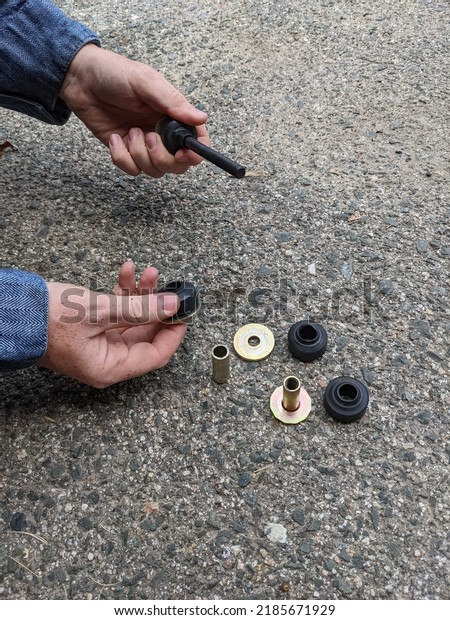 Mechanic Assembling a\
Sway Bar Part on the Floor of an Automotive Shop, Close Up Hands\
Working on Car Parts