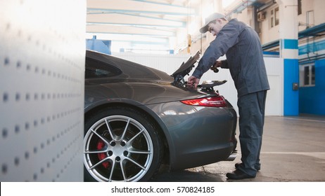 Mechanic In Automobile Garage Checking Hood For The Luxury Car, Close Up