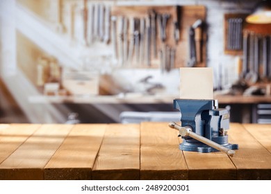 Mechanic bench vice on a wooden workbench in a craftsman's workshop. A blurred wall with tools in the background. Empty advertising space  for mounting products and objects. - Powered by Shutterstock