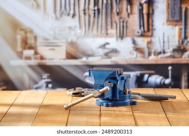 Mechanic bench vice on a wooden workbench in a craftsman's workshop. A blurred wall with tools in the background. Empty advertising space  for mounting products and objects. - Powered by Shutterstock