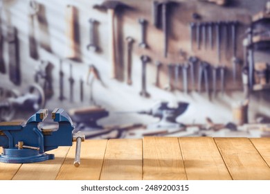 Mechanic bench vice on a wooden workbench in a craftsman's workshop. A blurred wall with tools in the background. Empty advertising space  for mounting products and objects. - Powered by Shutterstock