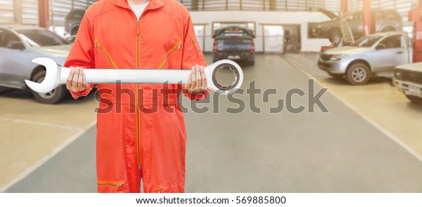 Mechanic with a big wrench in auto repair shop,\
Mechanic and tools\
concept.