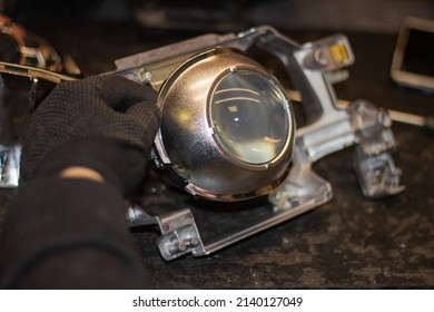 A mechanic in black gloves installs an LED lens into the headlight housing.Car headlight during repair and cleaning.The mechanic restores the headlight of the car.Restoration of automotive optics.