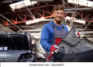 Mechanic with car bumper in a workshop
