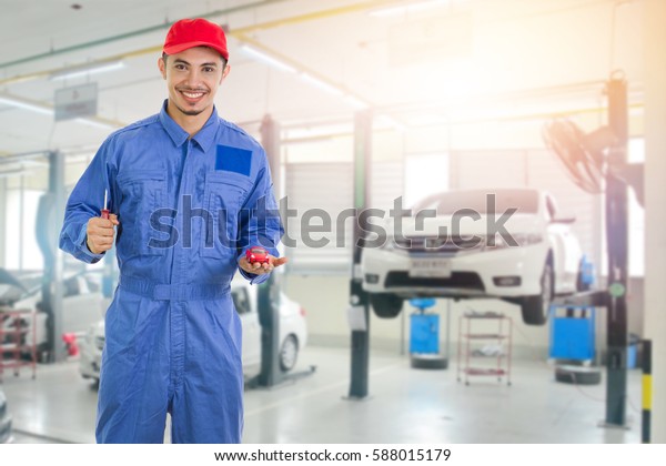 Mechanic with car model on his hand at the\
repair garage , service car concept\
