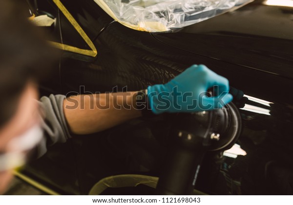 Mechanic with a car\
polisher in the\
workshop