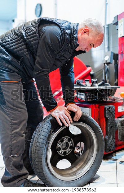 Mechanic in a car repair shop removing a tire from a\
vehicle\'s rim