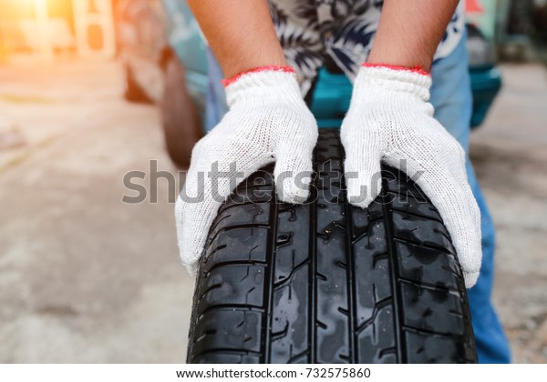 Mechanic change a car tyre on street with sun light\
effect  