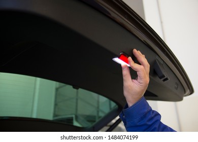 A mechanic changes the backlight. Work in a car service.