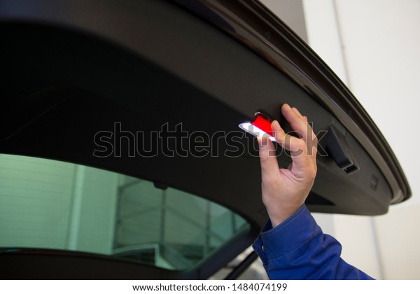 A
mechanic changes the backlight. Work in a car
service.