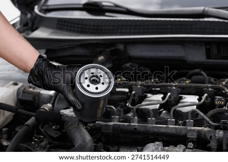 Mechanic changes filter. Mechanic professionally works on fuel filter during diesel engine maintenance. Close-up of fuel filter against background of engine compartment. Auto parts replacement concept