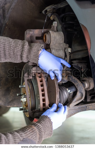 Mechanic changing the brake pads of a car\
and pressing the plunger of the brake\
caliper