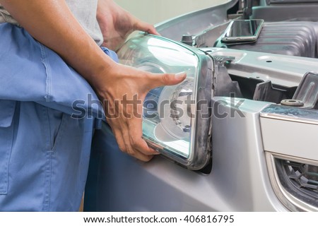Mechanic changing car headlight in a workshop