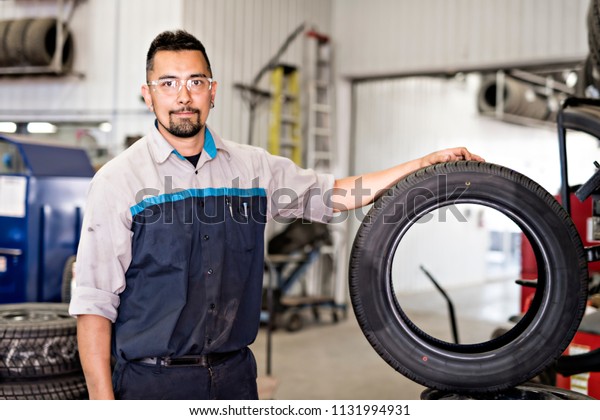 Mechanic changing car tire at\
work