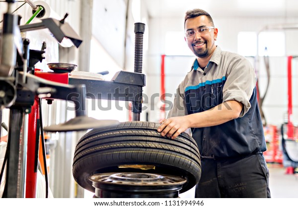 Mechanic changing car tire at\
work