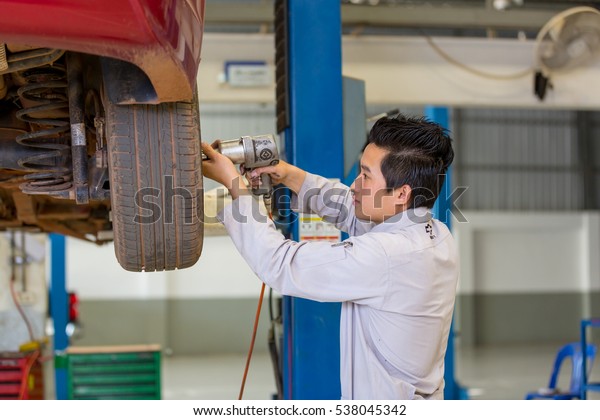 Mechanic changing car wheel at certified\
service garage. After Sale Service Chevrolet-Lao at Vientiane\
Capital, Laos. photo were taken on November 9\
2016.