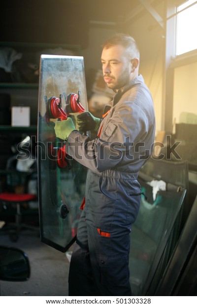 Mechanic changing\
glass for car in\
workshop.