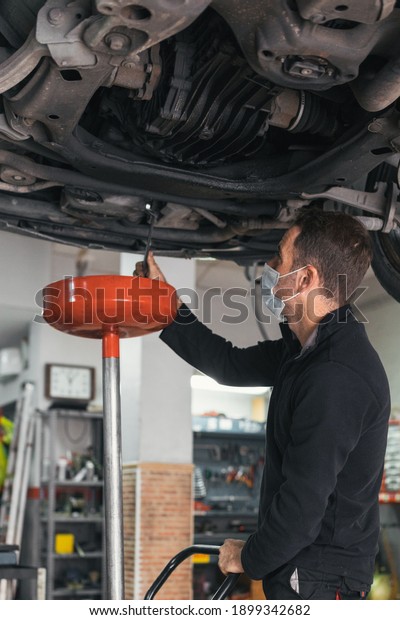 Mechanic changing the oil of the car. concept\
automobile mechanics.\
Covid19