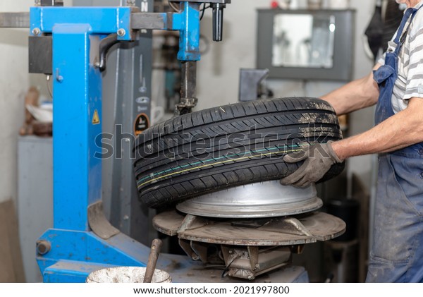 Mechanic changing tire in car service.\
Tire rotation machine.Car mechanic mounts tire on wheel in a\
workshop. tire installation in the\
workshop,closeup.