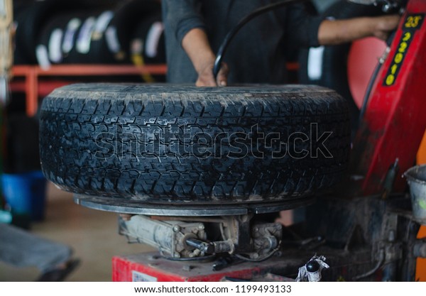 Mechanic changing tire indoor at the repair\
garage.Professional Tire installation Car Tire Replacement and\
Maintenance concept. 