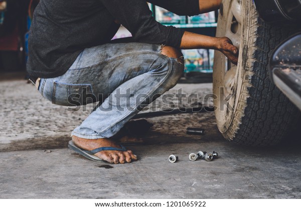 Mechanic changing tire indoor at the repair\
garage.Professional Tire installation Car Tire Replacement and\
Maintenance concept.\
