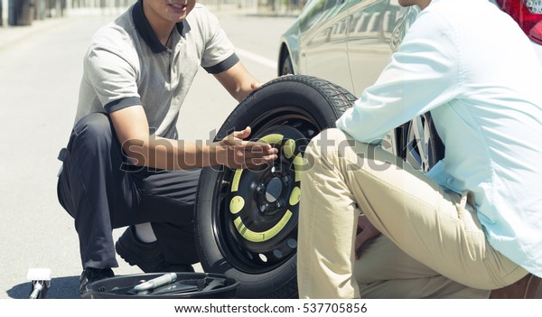mechanic changing tyre with\
customer