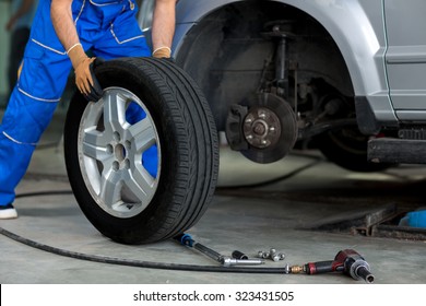 mechanic changing a wheel of a modern car  in a workshop - Powered by Shutterstock