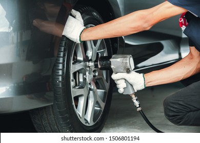 Mechanic changing wheel on car with impact wrench. mechanic man with electric screwdriver changing tire outside. Car service. Hands replace tires on wheels. - Powered by Shutterstock