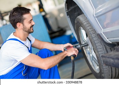 Mechanic changing wheel on car with impact wrench - Powered by Shutterstock