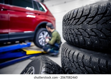 Mechanic changing wheel, replacement of winter and summer tires of modern car.