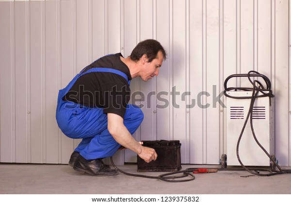 Mechanic charging the battery with a charger in\
the auto service