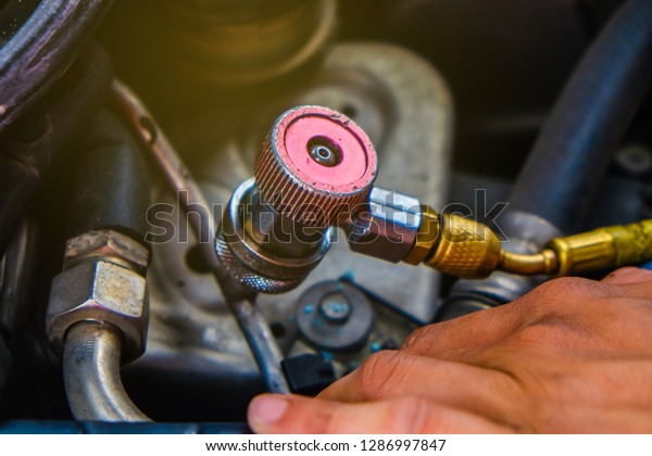 Mechanic check car air conditioner system in\
garage fix car air\
problem