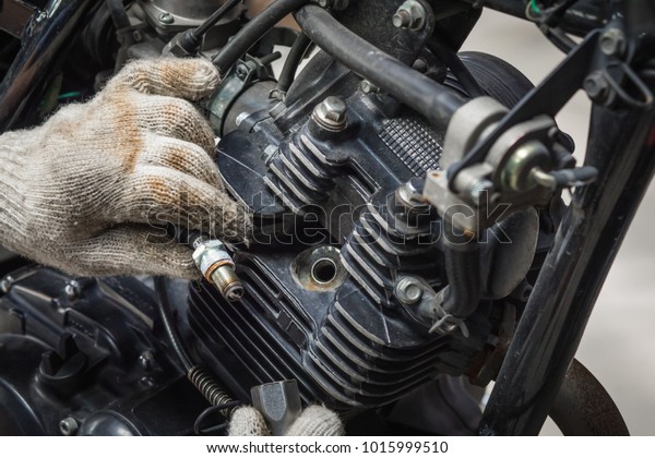 Mechanic Check Spark Plug Inspection and\
Maintenance, Inspection Prior to Installation in engine ignition\
and electrical systems at motorcycle garage.repair and maintenance\
motorcycle concept.
