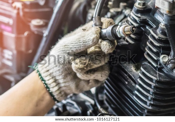 Mechanic Check Spark Plug and\
Maintenance, inspection Prior to Installation in engine ignition at\
motorcycle garage.repair and maintenance motorcycle\
concept.\
