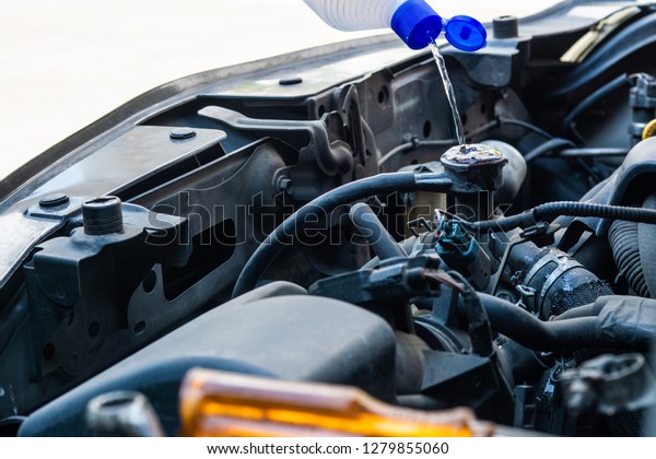 Mechanic Check water in Car radiator and\
Add water to car radiator, selective\
focus