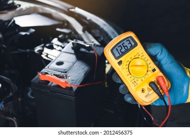 Mechanic Checking Car Battery Voltage With Digital Multimeter