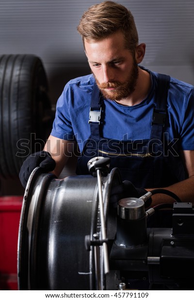 Mechanic checking car wheel\
rim.