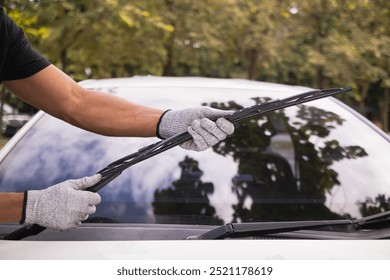 mechanic is checking car wiper blades to replace new wiper blades for car during the rainy season because when it rains it can be used at full efficiency. Checking and cleaning the car wiper blades - Powered by Shutterstock