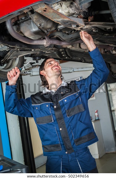 Mechanic checking\
the condition of a lifted\
car