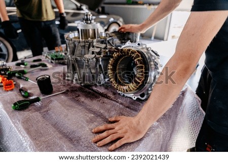 Mechanic checking engine. Disassembled electric car engine. Partially disassembled for repair motor of an modern electric vehicle. EV maintenance, service; repair concept.