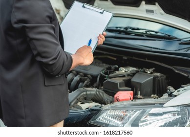 The mechanic is checking the engine and notes on a white paper. - Shutterstock ID 1618217560